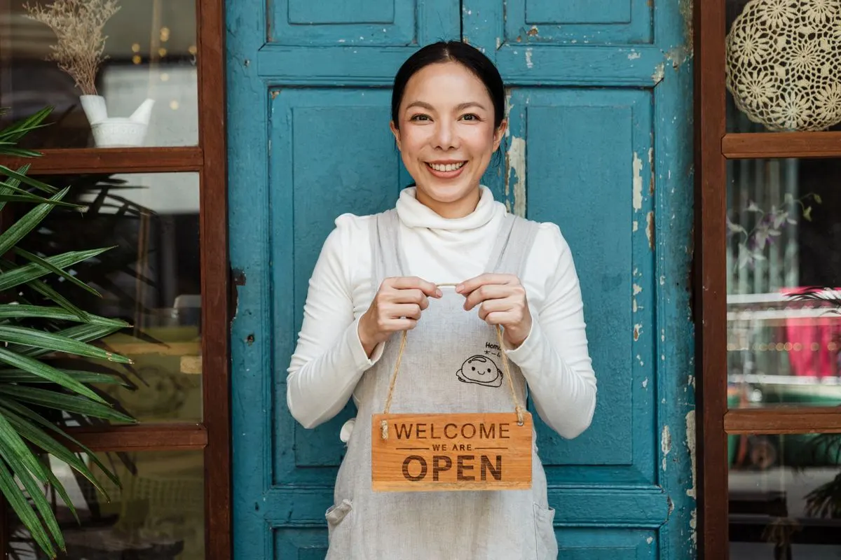 Smiling café owner holding a welcome sign